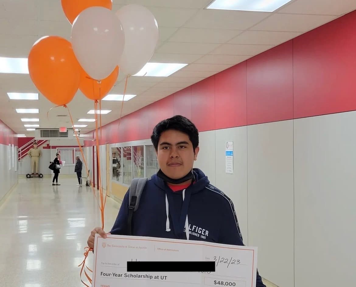 Student holding an oversized check for a $48,000 four-year scholarship to UT Austin